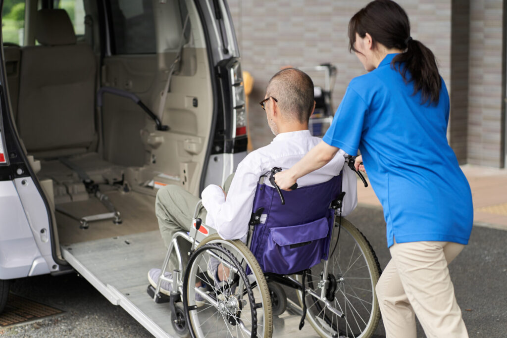 車イスの男性の乗車を補助するスタッフ